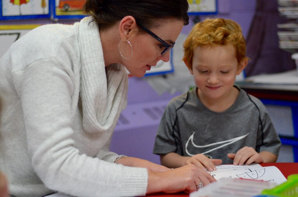teacher helping young boy with schoolwork