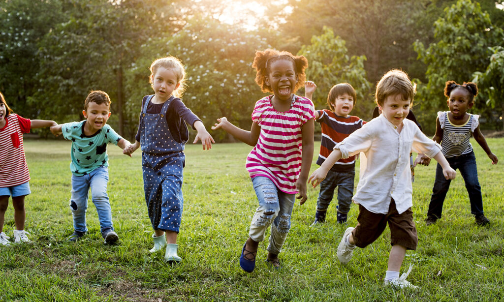 A group of young kids running in the grass