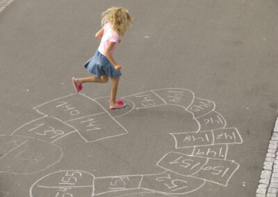 Little girl playing with her selfdesigned hopscotch.